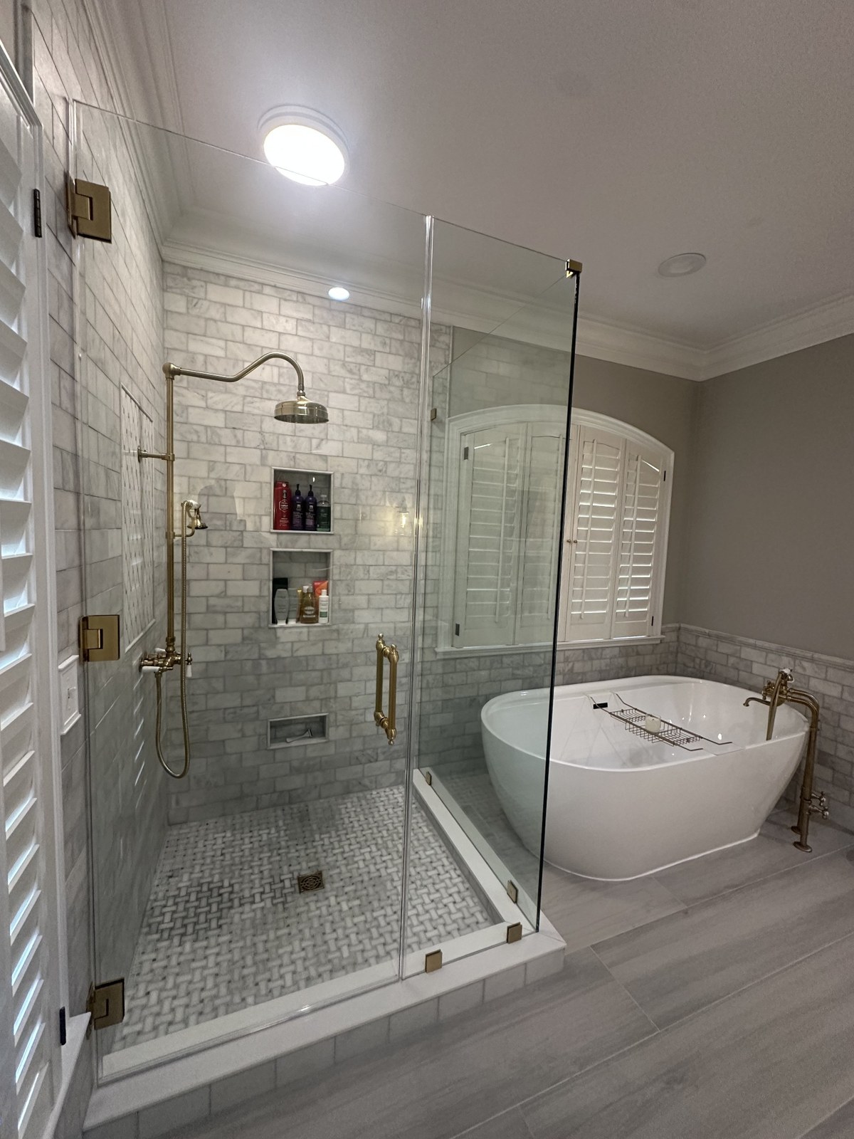 Custom shower glass door and panel beside a freestanding bathtub